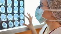 woman in scrubs and mask looking at imaging